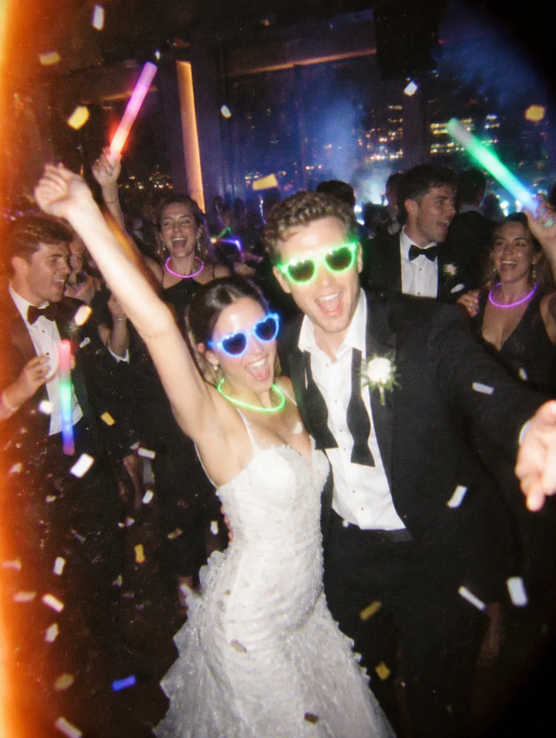 Bride and groom in party glasses dancing under confetti